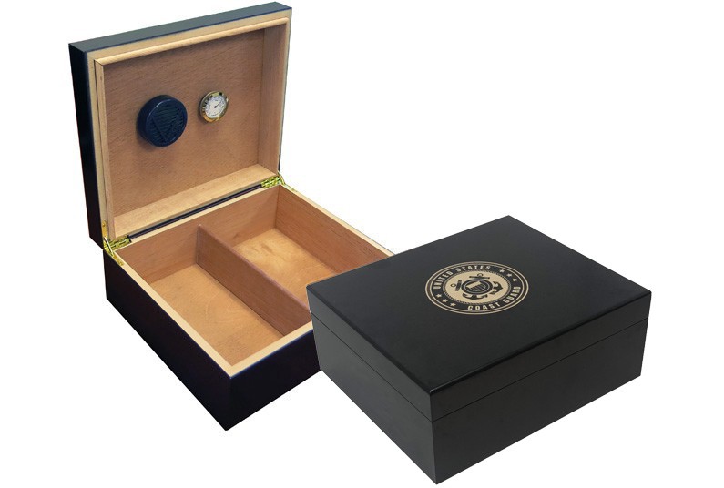 Two humidors in black finish one is open showing a humidifier and hygrometer the other one is closed with the US Coast Guard engraved on top